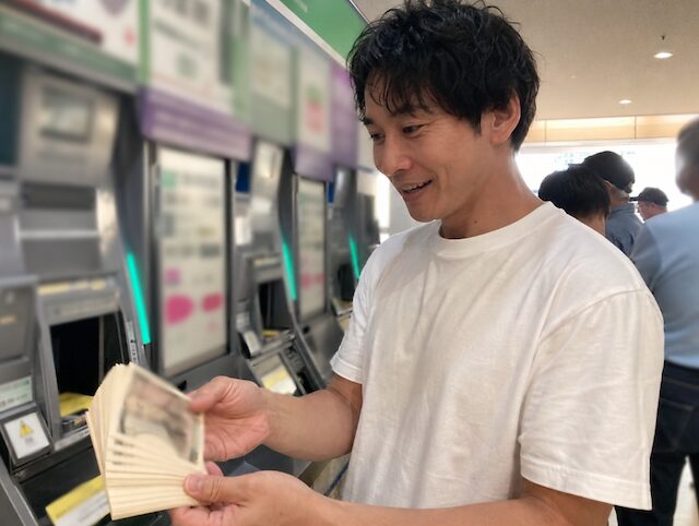 競馬場で馬券を購入し的中して払戻金を受け取った際の監修者前田智春の様子